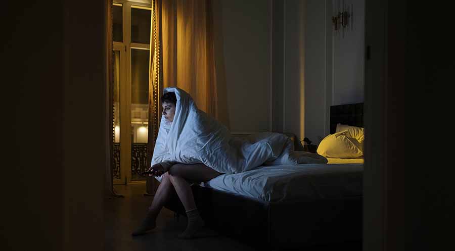 Une femme victime d'insomnie est assise au bord du lit, n'arrivant pas à dormir.